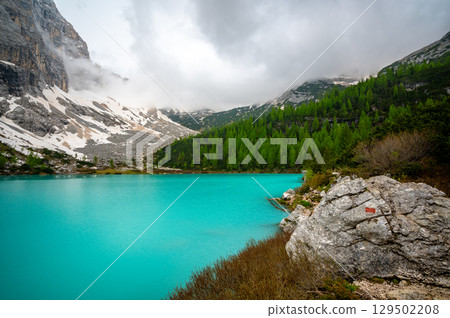 Panoramic view of Lago Sorapis in the Dolomites (Dolomiti, Dolomiten), Italy. The turquoise lake is surrounded by towering cliffs and mountains, a popular spot for hikers and nature lovers 129502208