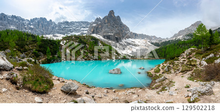 Panoramic view of Lago Sorapis in the Dolomites (Dolomiti, Dolomiten), Italy. The turquoise lake is surrounded by towering cliffs and mountains, a popular spot for hikers and nature lovers 129502218