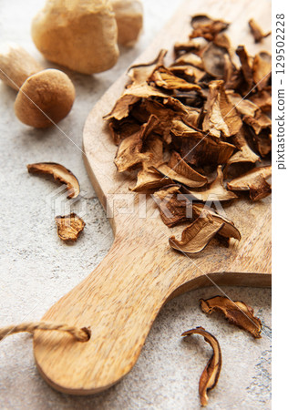 Dried mushrooms on wooden cutting board with fresh mushrooms 129502228