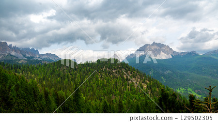 Breathtaking view of forests, mountains, and valleys in the Italian Dolomites (Dolomiti, Dolomiten). Captured from a scenic trail along a rocky ledge. Stunning alpine nature 129502305
