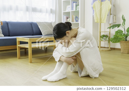 A young woman sitting on the living room floor 129502312