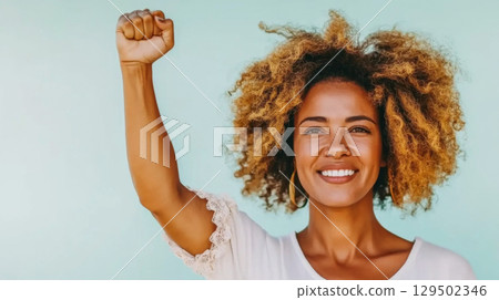 African american young woman with raised fist of empowerment and black women solidarity, International Womens Day, Black History Month concept 129502346