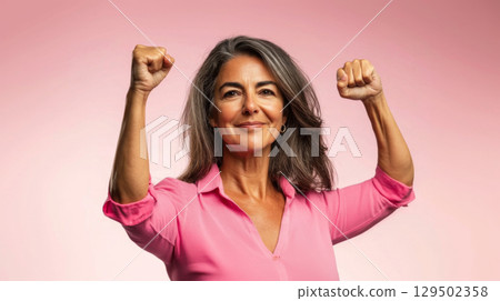 Middle aged latin american woman with raised fist of empowerment, strength and women solidarity, International Womens Day concept 129502358
