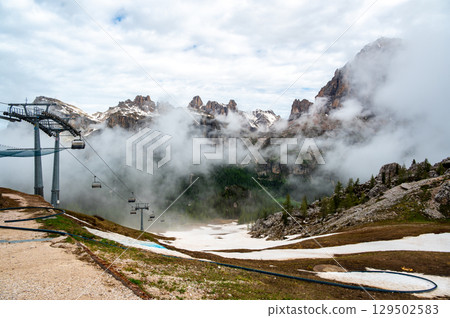 Mountain peaks around Cinque Torri in the Dolomites (Dolomiti, Dolomiten), Italy. Majestic summits partially covered in mist and clouds, with lush forests in the valleys below Mountain peaks around Cinque Torri in the Dolomites (Dolomiti, Dolomiten), Italy. Majestic summits partially covered in mist and clouds, with lush forests in the valleys below 129502583