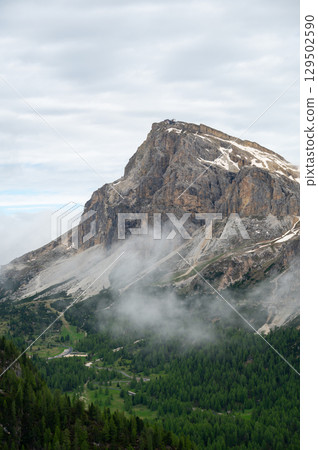 Mountain peaks around Cinque Torri in the Dolomites (Dolomiti, Dolomiten), Italy. Majestic summits partially covered in mist and clouds, with lush forests in the valleys below Mountain peaks around Cinque Torri in the Dolomites (Dolomiti, Dolomiten), Italy. Majestic summits partially covered in mist and clouds, with lush forests in the valleys below 129502590