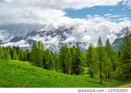Mountain peaks around Cinque Torri in the Dolomites (Dolomiti, Dolomiten), Italy. Majestic summits partially covered in mist and clouds, with lush forests in the valleys below Mountain peaks around Cinque Torri in the Dolomites (Dolomiti, Dolomiten), Italy. Majestic summits partially covered in mist and clouds, with lush forests in the valleys below 129502605