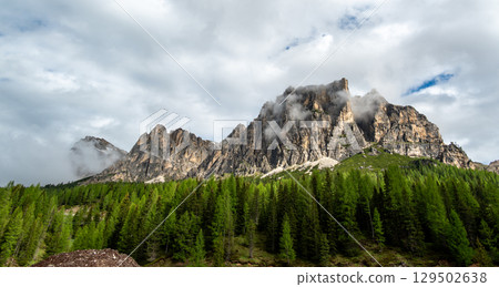 Mountain peaks around Cinque Torri in the Dolomites (Dolomiti, Dolomiten), Italy. Majestic summits partially covered in mist and clouds, with lush forests in the valleys below Mountain peaks around Cinque Torri in the Dolomites (Dolomiti, Dolomiten), Italy. Majestic summits partially covered in mist and clouds, with lush forests in the valleys below 129502638