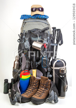 Essential hiking gear arranged neatly with a backpack, boots, and outdoor supplies 129503418