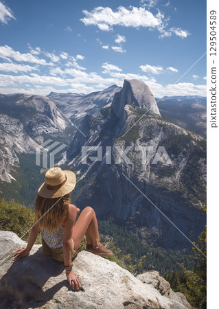 Young woman sitting on cliff edge overlooking famous landmark 129504589