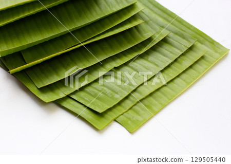 Stacked banana leaves on a white background, commonly used in traditional cooking. 129505440