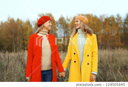 Happy young two women friends in autumn park, stylish girlfriends smiling together Happy young two women friends in autumn park, stylish girlfriends smiling together 129505845