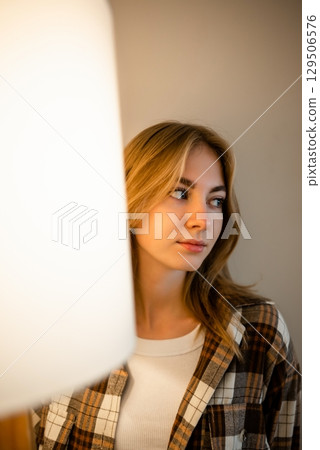 Woman in checkered shirt looking away with soft smile Woman in checkered shirt looking away with soft smile 129506576