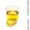 Amber plum wine is served in a slightly iridescent, transparent glass with water droplets reflected on a white background. 129507269