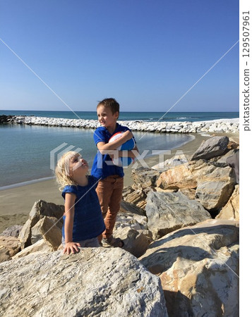 Children Enjoying a Day by the Ocean on Rocky Shore Children Enjoying a Day by the Ocean on Rocky Shore 129507961