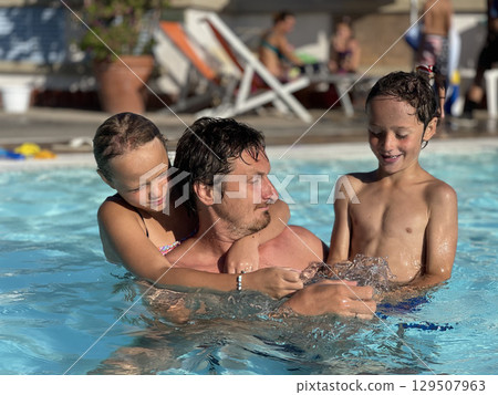 Father Enjoys Pool Time with Happy Children Father Enjoys Pool Time with Happy Children 129507963