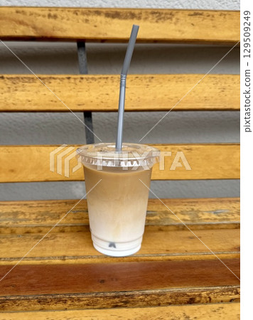 Takeaway iced cafe au lait on an outdoor bench 129509249
