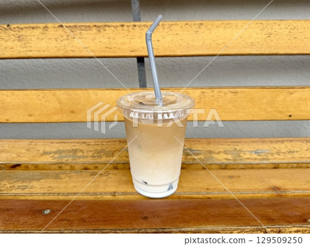 Takeaway iced cafe au lait on an outdoor bench 129509250
