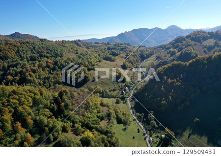 Aerial view of village dirt road in the mountains. Autumn forest 129509431