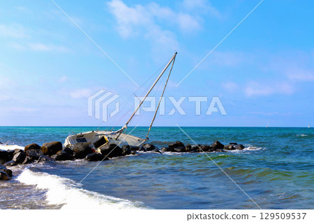 Sunny beach with sand and sea, broken yacht far in distance. 129509537