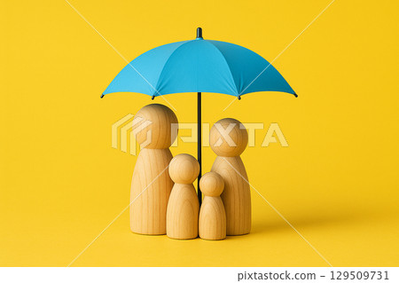 Wooden peg figurines representing a family standing under a blue umbrella on a yellow background symbolizing protection and security 129509731