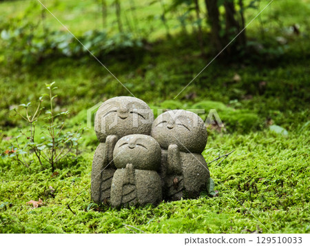 Jizo statue standing in a mossy garden Jizo statue standing in a mossy garden 129510033