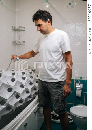 Vertical portrait of gardener male holding shower head, watering hydroponic system in bathroom, showcasing sustainable and innovative approach to indoor gardening. Concept of home gardening. Vertical portrait of gardener male holding shower head, watering hydroponic system in bathroom, showcasing sustainable and innovative approach to indoor gardening. Concept of home gardening. 129510077