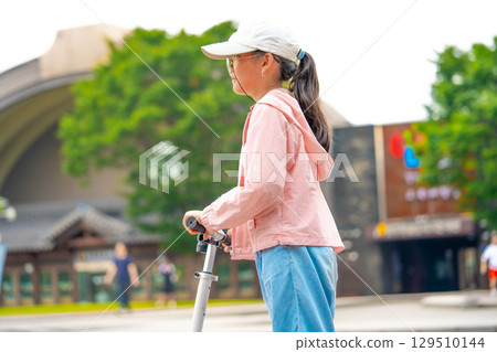 Asian girl is going to ride a scooter. Copy space 129510144