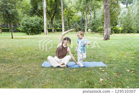 Mother and Toddler Doing Yoga in Summer Park 129510307