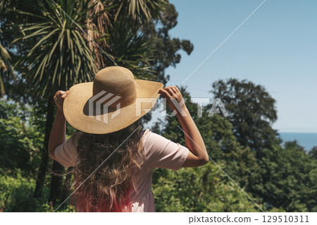 Woman with Straw Hat Looking at Lush Forest Woman with Straw Hat Looking at Lush Forest 129510311