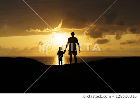 Father and Son Silhouettes at Sunset. Family Bonding Moment 129510316