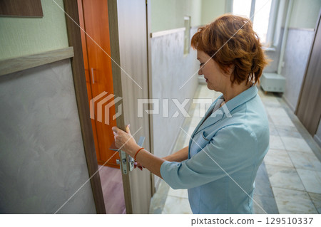 Woman opening the door to her office at the start of the workday. Entry, new beginning, and everyday professional routine. 129510337
