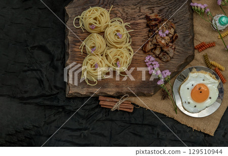 Spaghetti with Roasted Chicken with Black Pepper on a wooden plate Served with Fried Egg and Crispy butter toast. 129510944