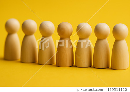 A row of natural figurines with a red figurine at the front symbolizing leadership and direction 129511120