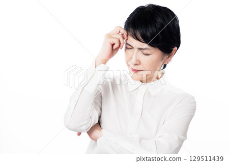 A middle-aged woman wearing a white shirt who is worried 129511439