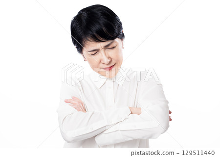 A middle-aged woman with her arms crossed and frowns 129511440