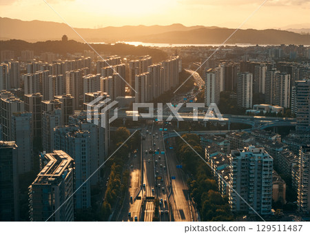 Aerial view of a residential buildings alongside a multilane highway interchange filled with moving vehicles 129511487