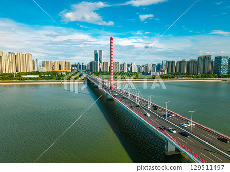 Aerial daytime view of cars and buses crossing Qiantang River Bridge in Hangzhou, China with city skyline. 129511497