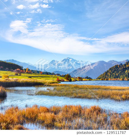 Fabulous autumn view of Haidersee (Lago della Muta) lake with Ortler peak on background. 129511787