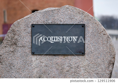Corporate acquisition and merger concept. Copy space. ACQUISITION text written on the plaque of a large stone monument. Corporate acquisition and merger concept. Copy space. ACQUISITION text written on the plaque of a large stone monument. 129511906