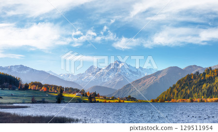 Gorgeous autumn view of Haidersee (Lago della Muta) lake with Ortler peak on background. 129511954