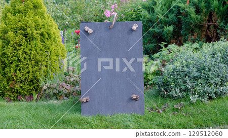 Slate sign with rope detail set against a garden backdrop. Copy space. 129512060