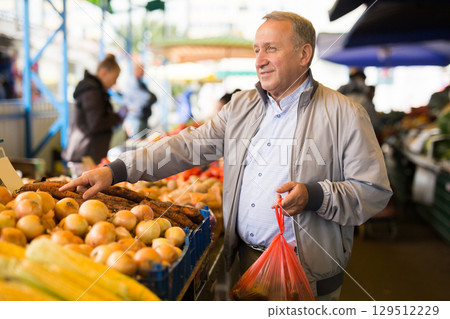 Man choosing vegetables in greengrocery Man choosing vegetables in greengrocery 129512229