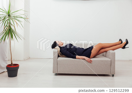 woman in black dress lying on gray sofa 129512299