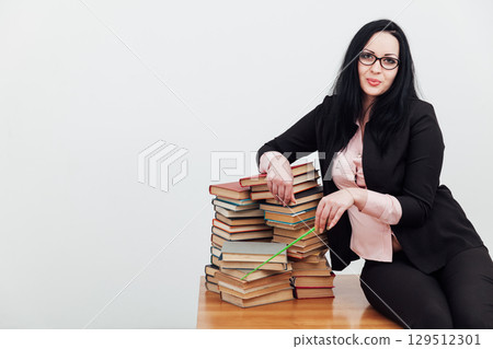 teacher with stacks of books on table 129512301