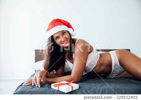 Woman in lingerie with gift in bedroom on bed for new year 129512455