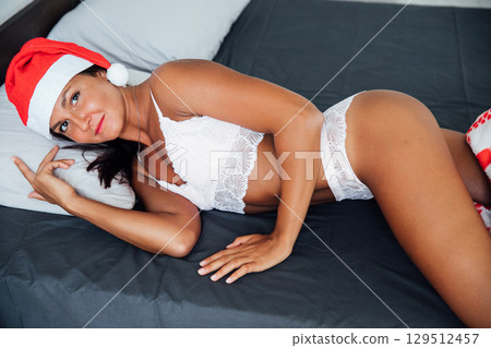 Woman in lingerie with christmas gift in bedroom on bed for new year Woman in lingerie with christmas gift in bedroom on bed for new year 129512457