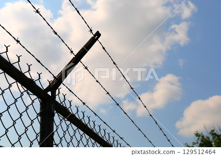 barbed wire fence against blue sky description barbed wire fence against blue sky description 129512464