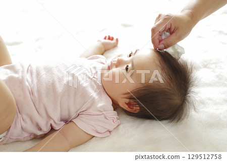 A mother gently wipes her baby's face 129512758