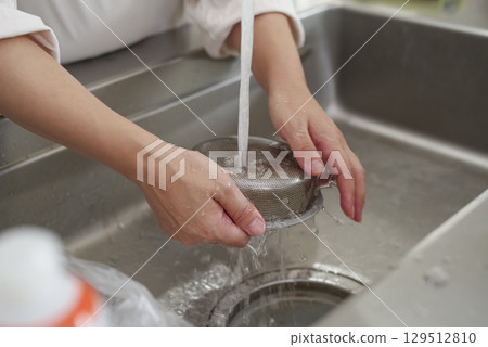 清潔廚房排水過濾器的手 129512810