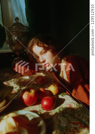 A woman is laying on a table with a bowl of apples and a vase 129512910